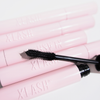 Auf weißem Hintergrund liegt eine schwarze Lash Hero-Mascara-Bürste auf rosa XLASH-Tuben.