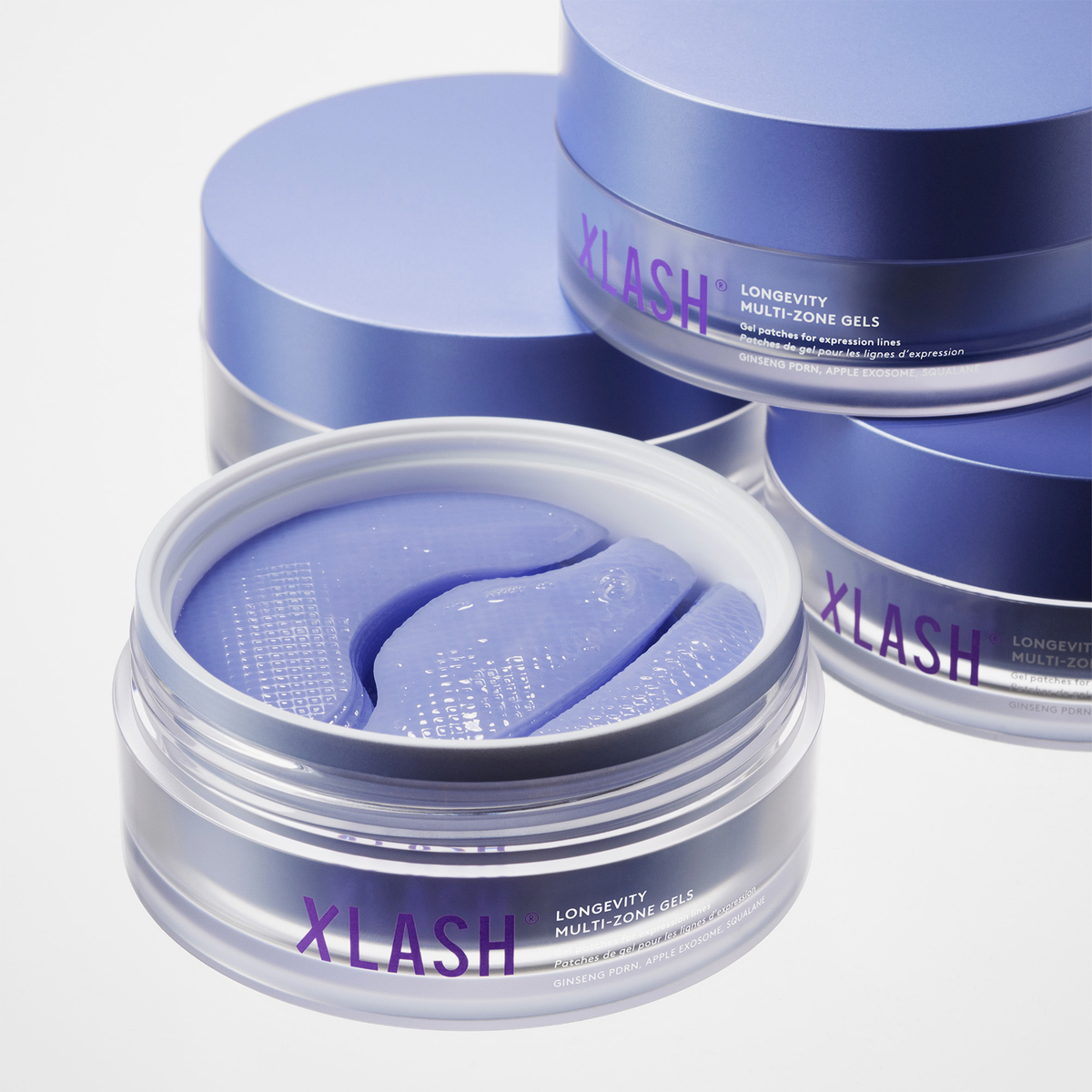 Drei übereinander gestapelte Gläser mit violetten XLASH Longevity Multi-Zone-Gel-Augenpads.