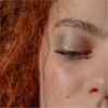 Nahaufnahme eines Gesichts mit lockigem rotem Haar, einem Schönheitsfleck und schimmerndem GLOWEYE EYESHADOW von BLONDESISTER.