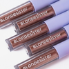Vier Tuben BLONDESISTER GLOWEYE EYESHADOW in einem braunen Metallic-Farbton, diagonal auf einem weißen Hintergrund angeordnet.