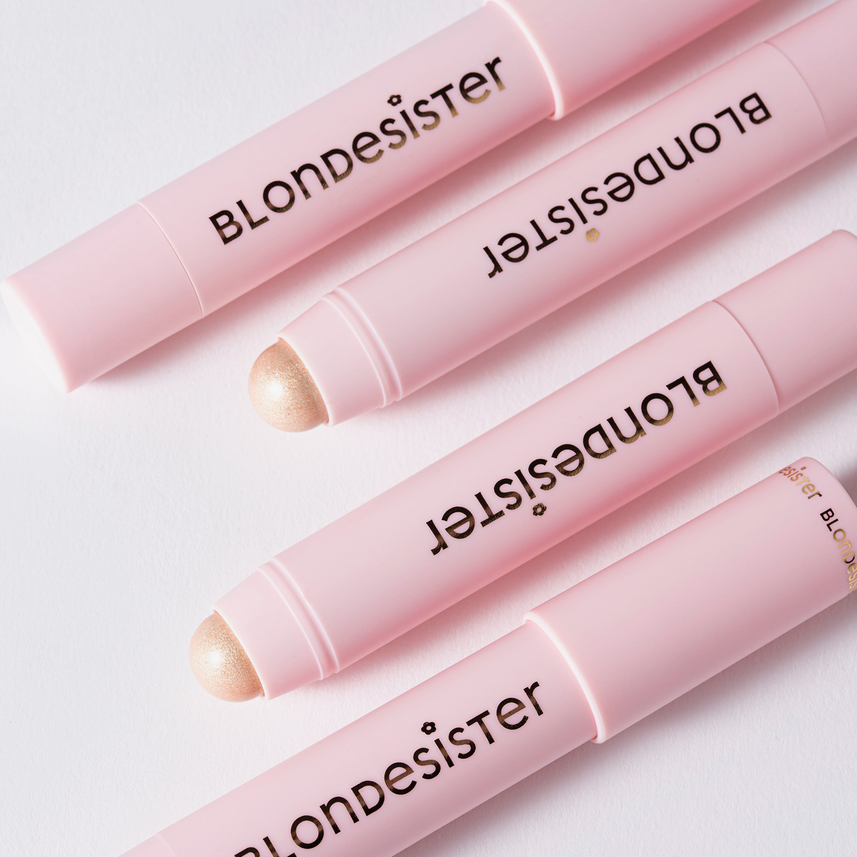 Vier READY TO GLOW HIGHLIGHTER CRYSTAL MOOD 01-Stifte von BLONDESISTER sind diagonal auf einem weißen Hintergrund angeordnet.