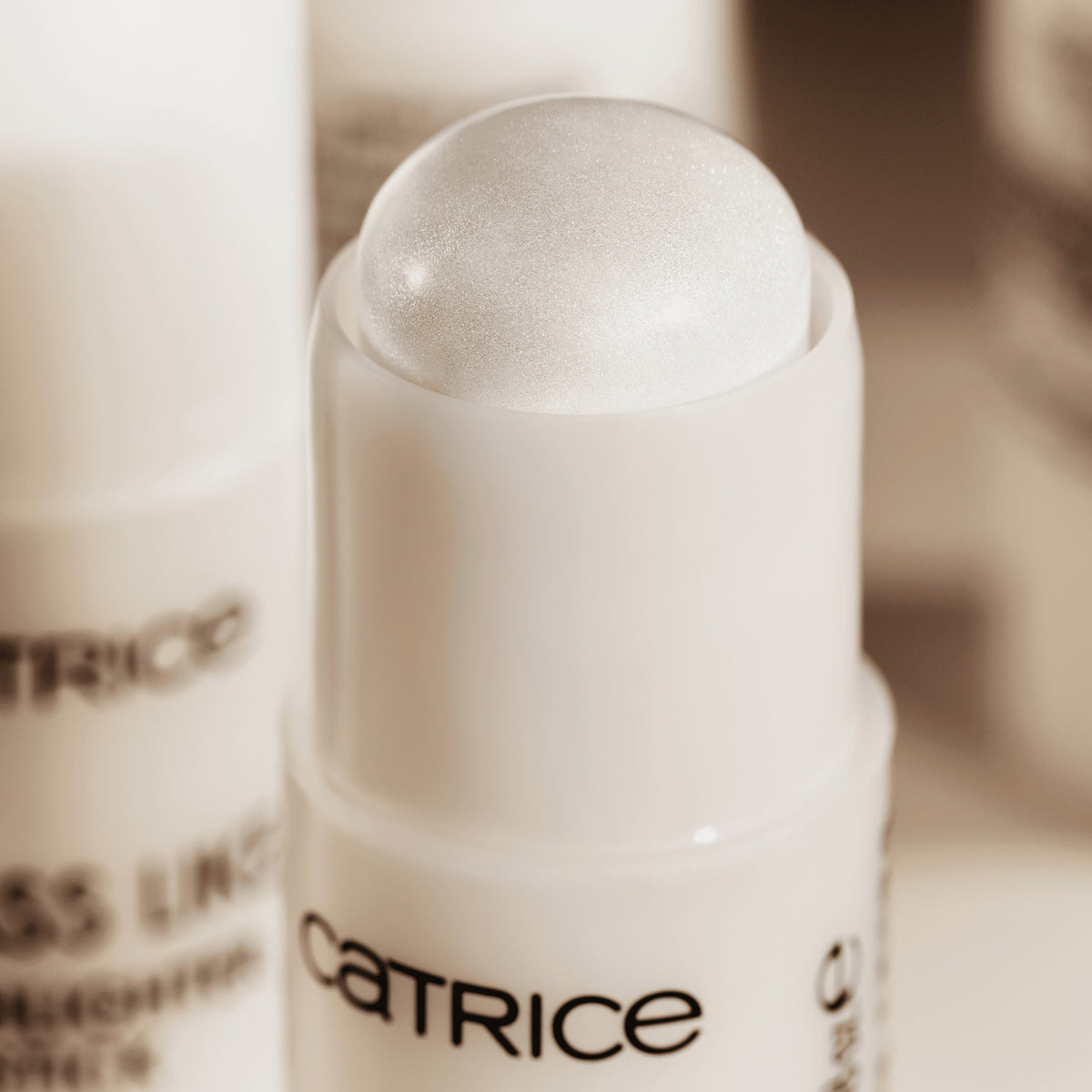Eine Nahaufnahme des geöffneten Glass Like Highlighter Stick 010 mit einer perlweiß schimmernden Spitze in einer schlichten weißen Tube.