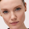Eine Frau mit heller Haut, blauen Augen und natürlichem Make-up trägt die Catrice Cosmetics Hyper Lash Mascara 010 und blickt direkt in die Kamera.