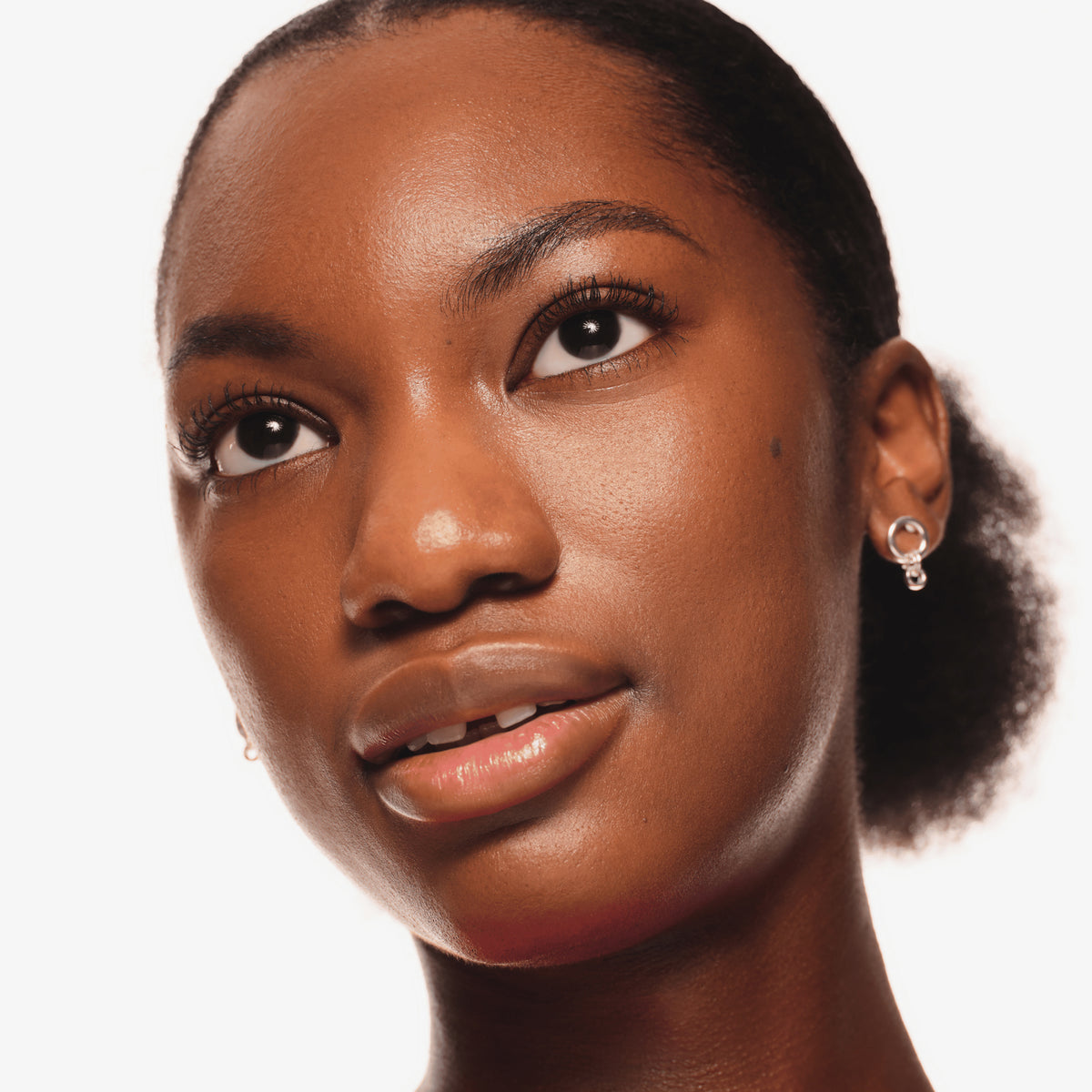 Nahaufnahme eines Gesichts mit natürlichem Make-up und dezent getuschten Wimpern, die den Augen einen offenen, strahlenden Look verleihen.