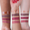 Drei Arme mit unterschiedlichen Hauttönen zeigen vier Farbtöne des „Over The Garden Wall Potatoes & Molasses Swirled Lip Gloss“ von Lethal Cosmetics.