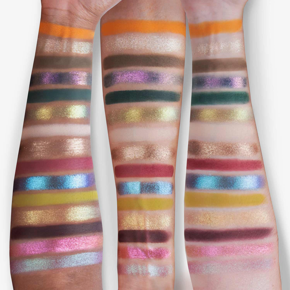 Auf drei Unterarmen sind Farbmuster der Lidschatten aus der „Over The Garden Wall – Tome of the Unknown“-Palette von Lethal Cosmetics zu sehen.
