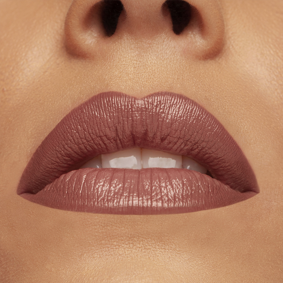 Nahaufnahme der Lippen einer Frau, die das CULT CREAMY LIP KIT von Mesauda Beauty in einem matten Mauve-Ton trägt, leicht gescheitelt, um weiße Zähne und glatte Haut zu zeigen.