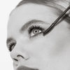 Schwarz-Weiß-Nahaufnahme einer Frau, die THE GLAM FEMULINE Mascara von Mesauda Beauty mit einem Zauberstab auf ihre Wimpern aufträgt.