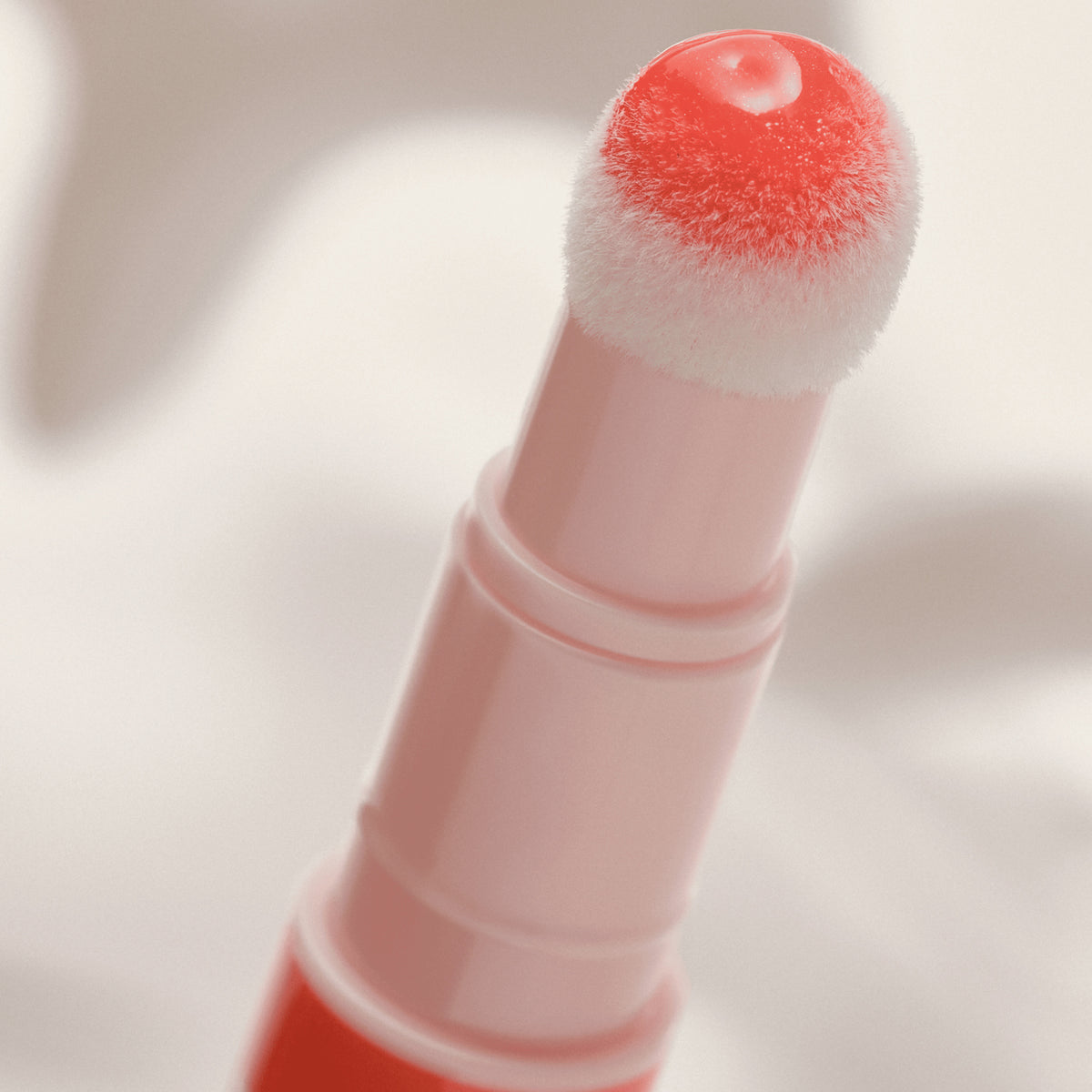 Eine Nahaufnahme des Catrice Cosmetics Colour Cushion Juicy Lip Oil mit weichem, abgerundetem Schwammapplikator und rot getöntem Finish für Lippen und Wangen.
