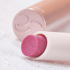 Nahaufnahme des Catrice Diamond Glaze Gloss Stick in einem schimmernden Rosaton, liegend mit sichtbarer Produktspitze und rosigem Deckel im Hintergrund.