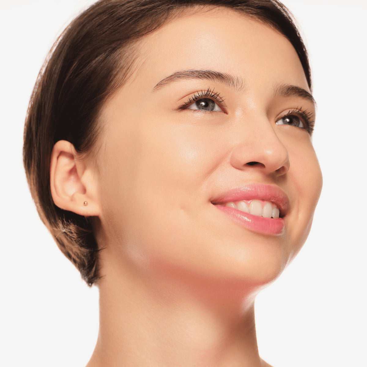Lächelnde Person mit dezentem Make-up und sanft getuschten Wimpern, die den Augen einen frischen, natürlichen Look verleihen.