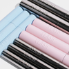 Hellblaue, rosa und silberne Tuben der XLASH Weightless Mascara, die in einem ordentlichen, sich überlappenden Muster auf einer weißen Fläche angeordnet sind.