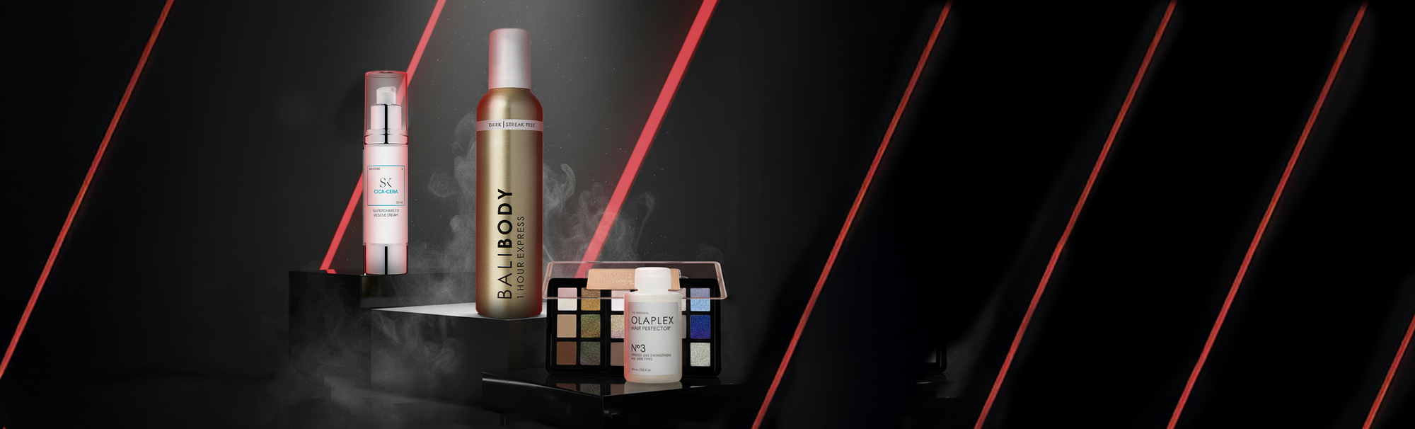 Vier Beauty-Produkte vor dunklem Hintergrund mit roten Lichtstreifen: Skintegra Cica-Cera, Bali Body 1 Hour Express, Danessa Myricks Palette und OLAPLEX No.3.