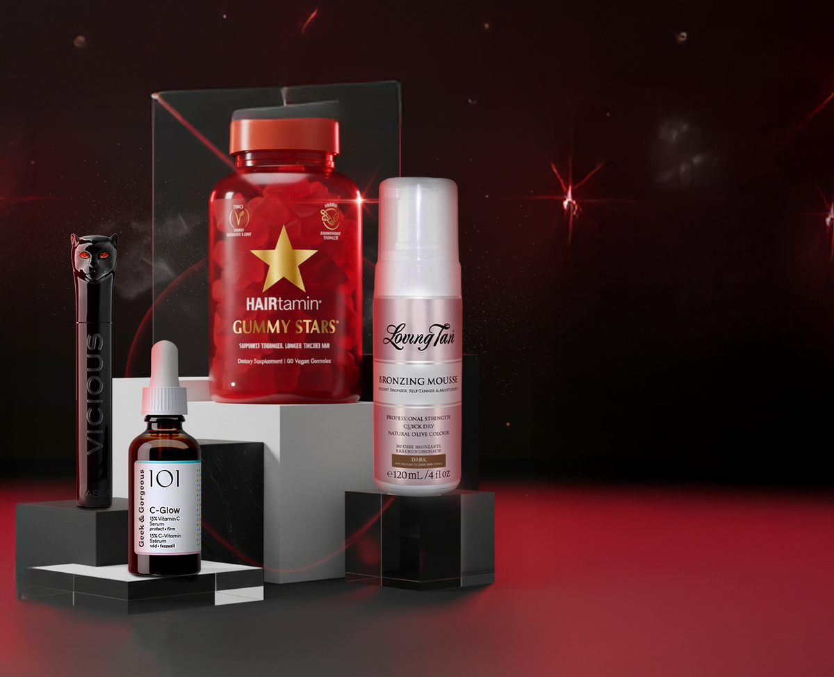 Vier Beauty-Produkte auf schwarzen Podesten vor dunklem Hintergrund mit roten Lichtakzenten: Geek & Gorgeous C-Glow Serum, Hairtamin Gummy Stars, NABLA Vicious Mascara und Loving Tan Bronzing Mousse.
