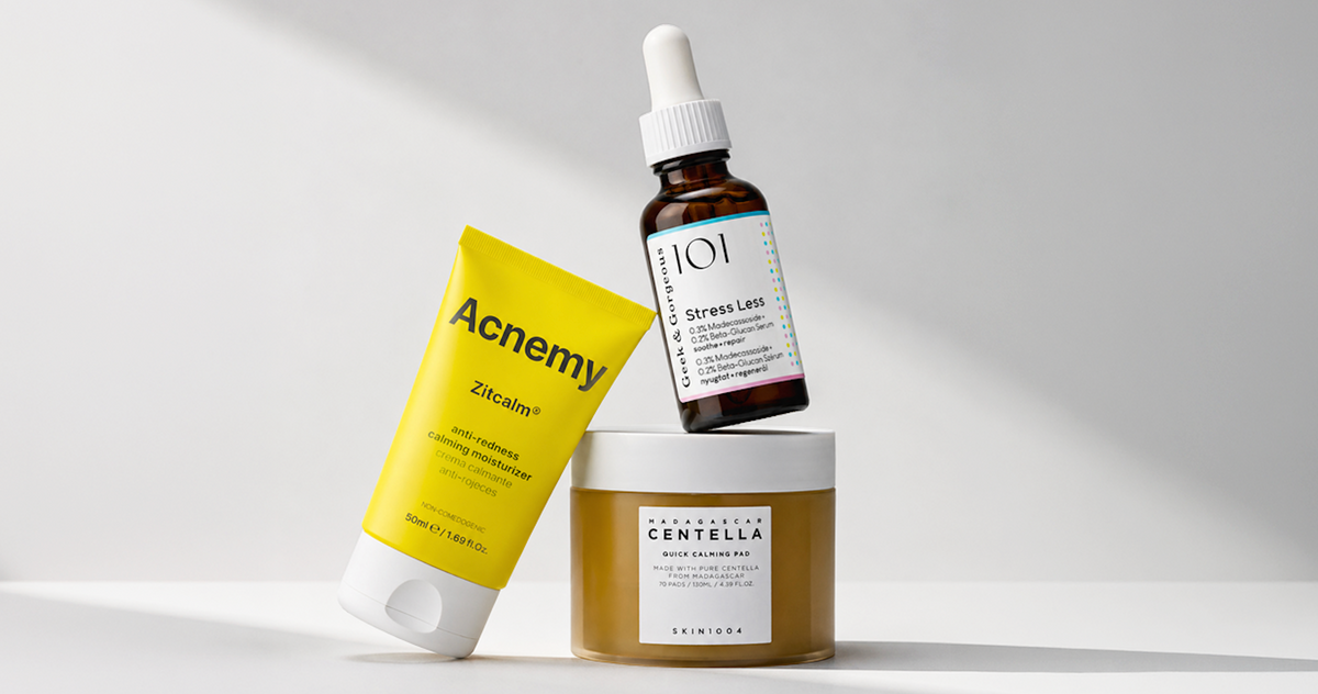 Drei Hautpflegeprodukte, darunter eine gelbe Aknecreme, eine braune Serumflasche und ein Tiegel mit Reinigungsbalsam.