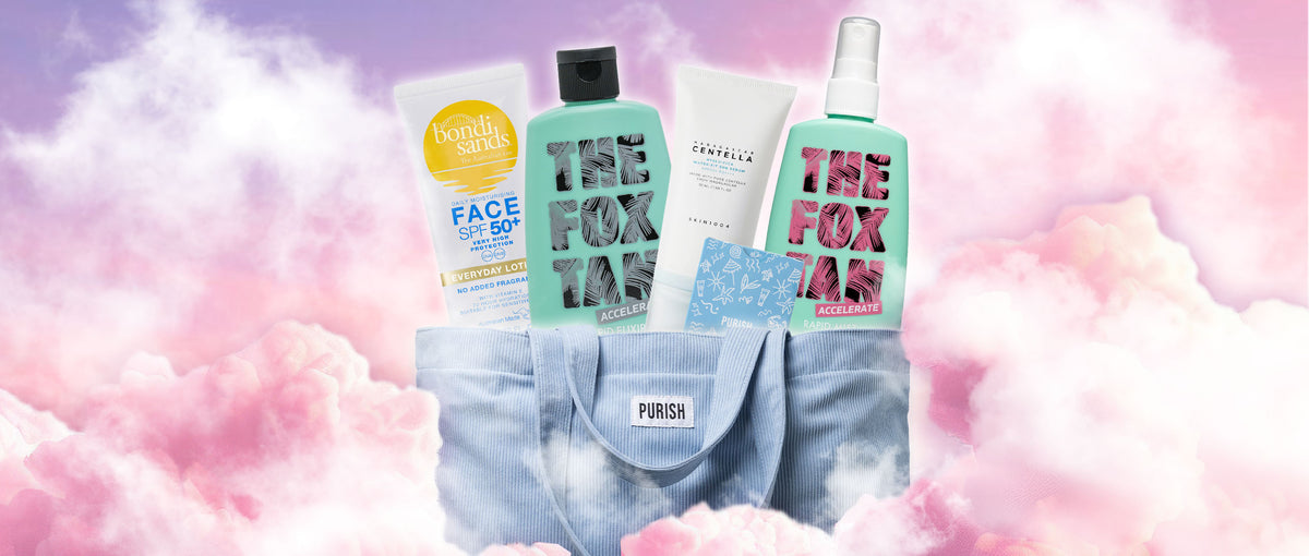 Eine hellblaue Purish-Tasche gefüllt mit Hautpflegeprodukten von Bondi Sands, The Fox Tan und SKIN1004, vor rosa Wolkenhintergrund.