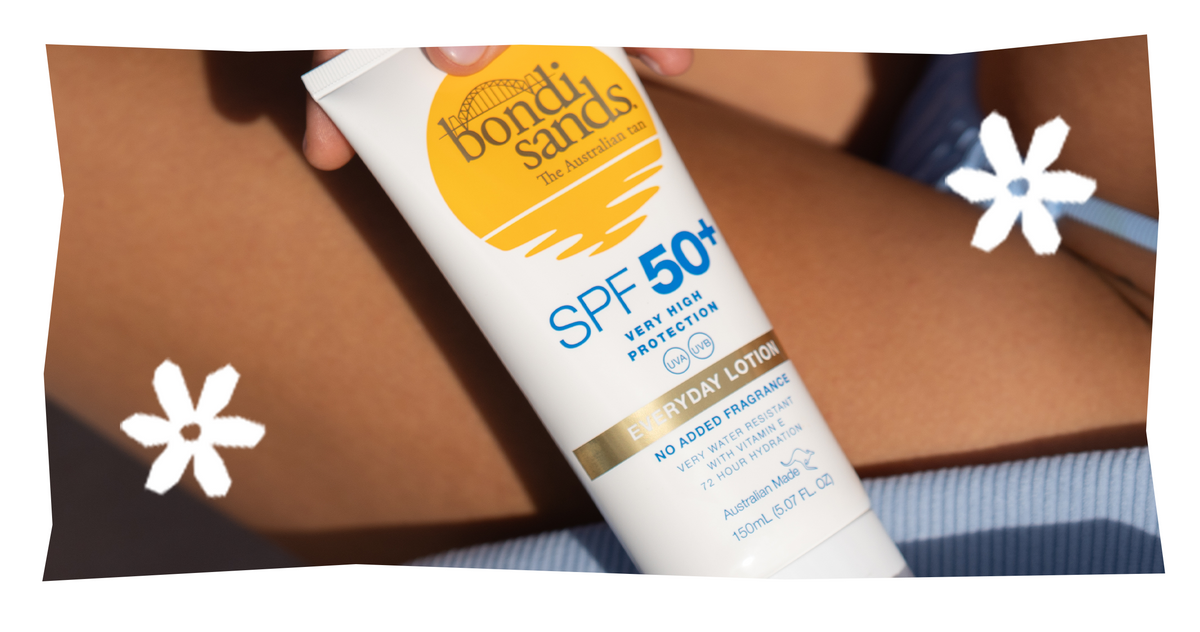 Eine Person hält Bondi Sands SPF 50+ Sonnenschutzmittel in der Hand; im Hintergrund sind ihre Beine und ihr blauer Badeanzug zu sehen.