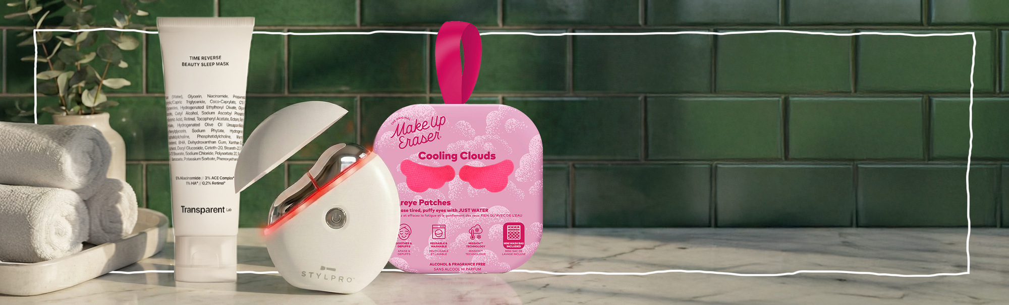 Transparent Lab Beauty Sleep Mask, STYLPRO Gerät und Makeup Eraser Cooling Clouds Augenpads auf Marmorablage vor grünen Fliesen.