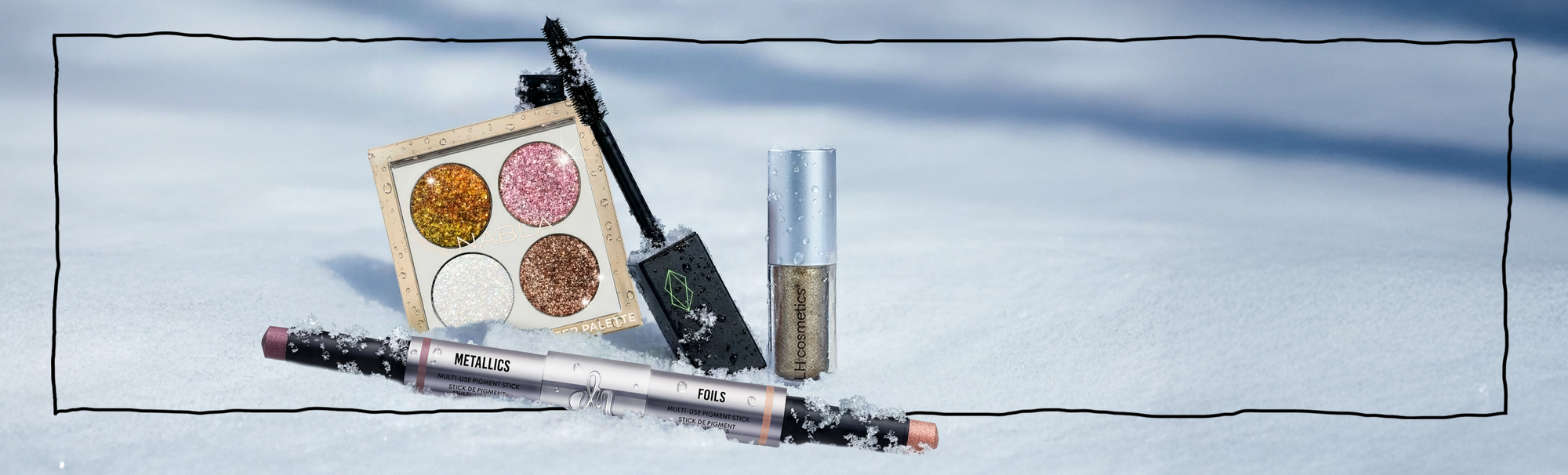 NABLA Glitter Palette, Lethal Cosmetics Mascara, LH Cosmetics Sparkl und Danessa Myricks Duo Stix liegen im Schnee und funkeln in der Sonne.