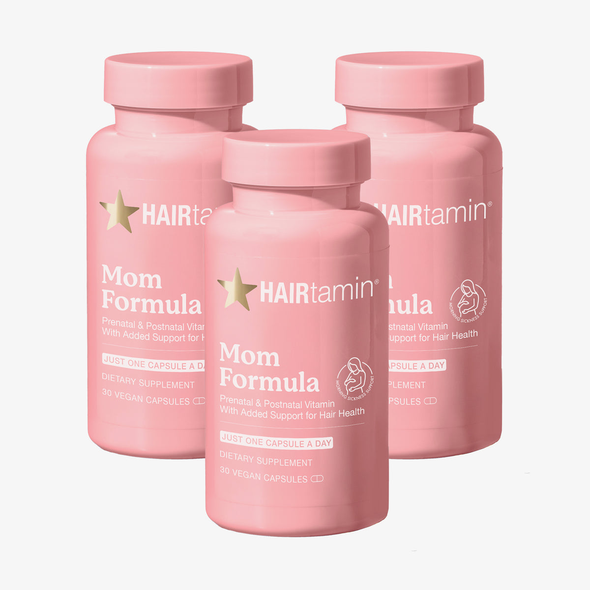 Drei rosa Flaschen des MOM Formula HAIRtamin auf weißem Hintergrund.
