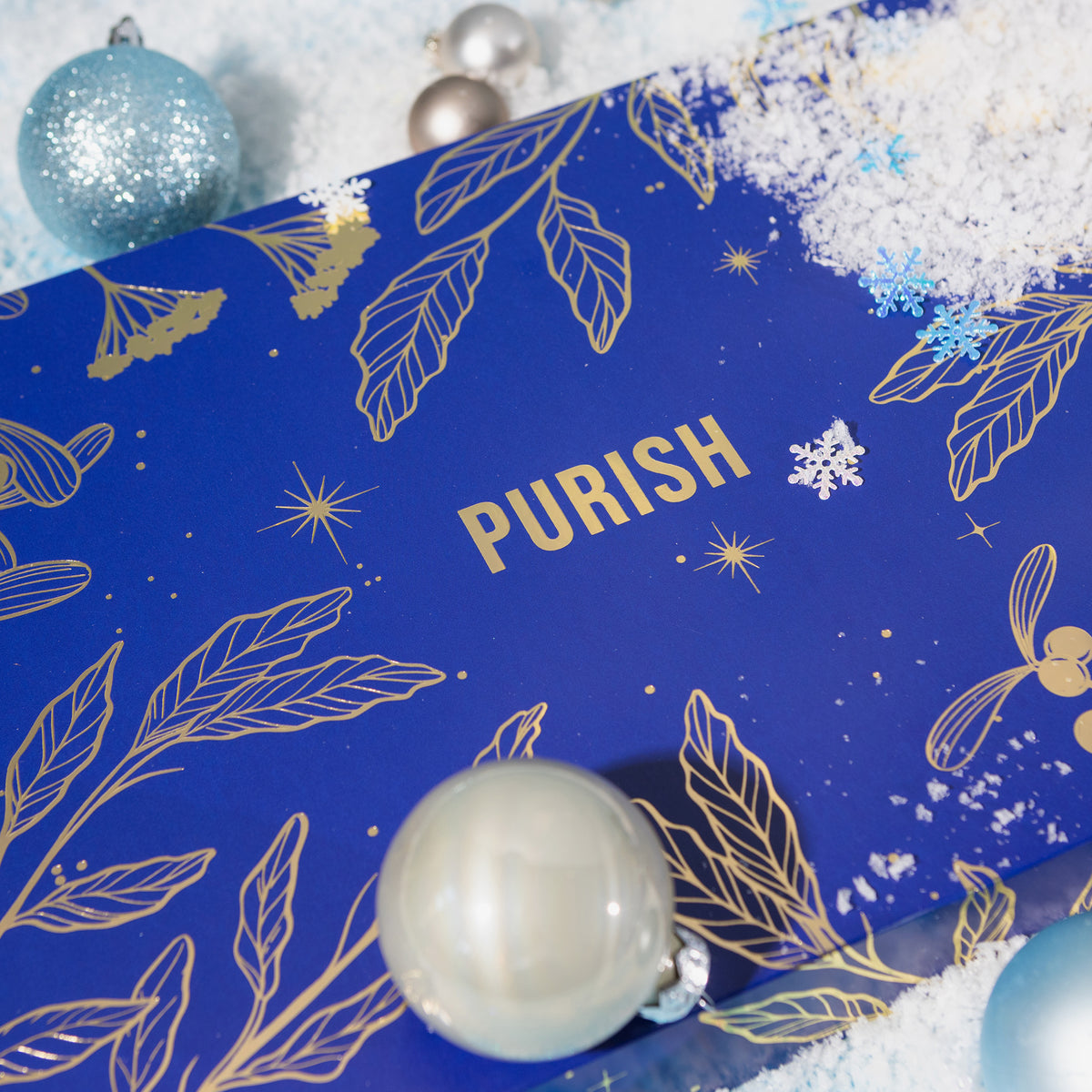 Sneak Peak des PURISH Beauty Adventskalender 2024 unter Schnee und Weihnachtskugeln