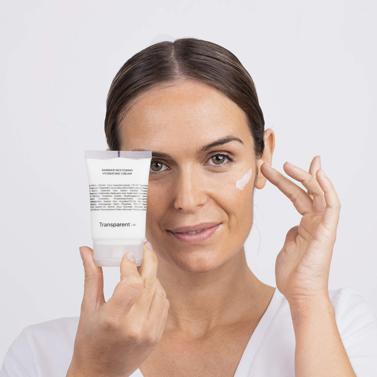 Eine Person, die die Transparent Lab Barrier Restoring Hydrating Cream auf ihr Gesicht aufträgt